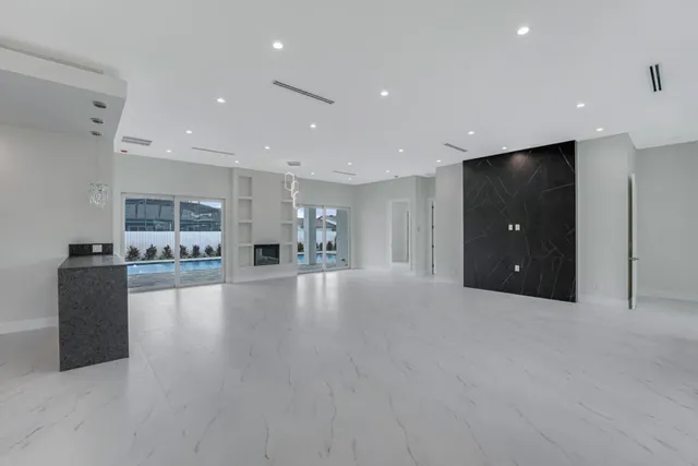 a view of an empty room with kitchen and a refrigerator