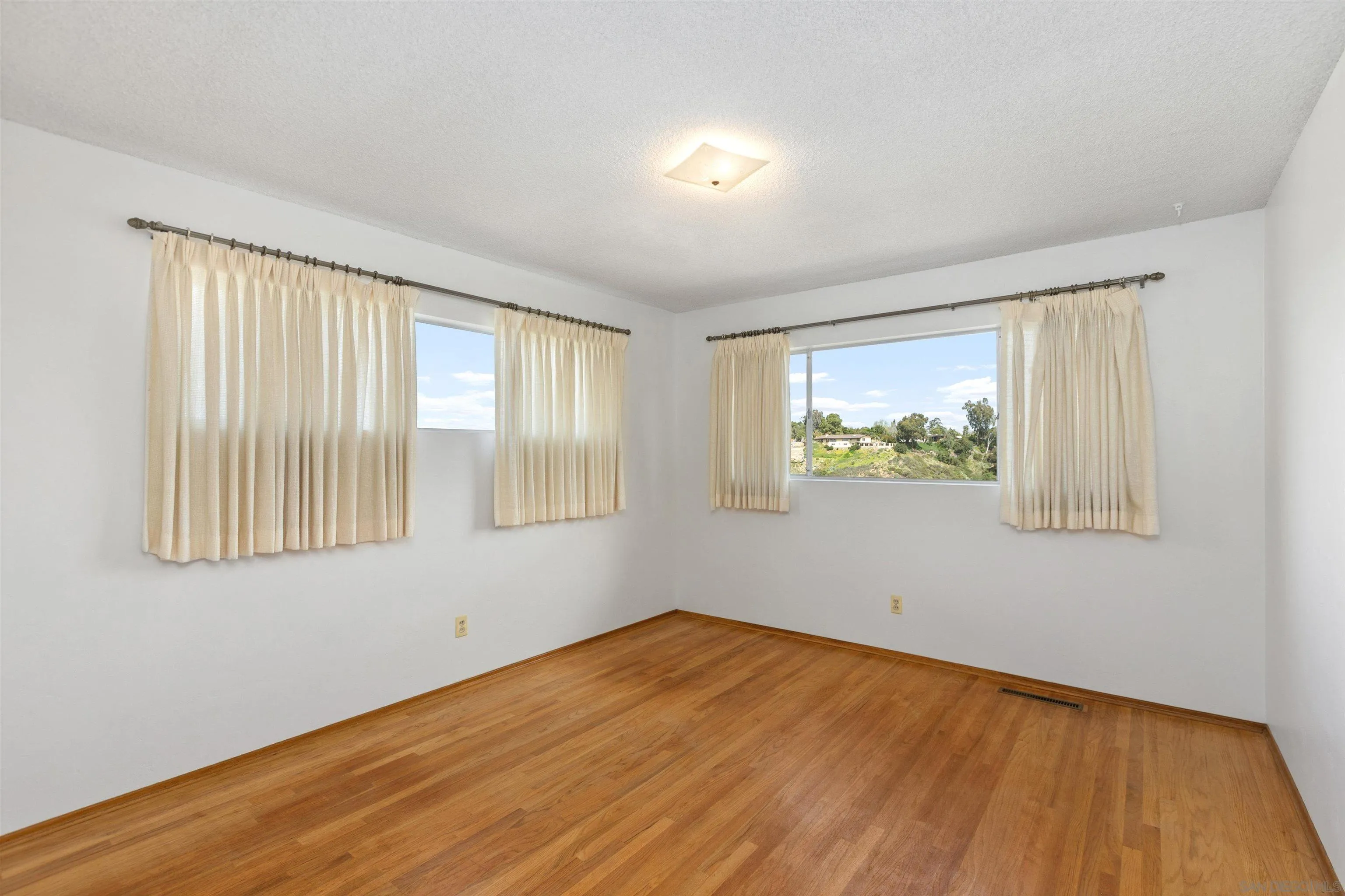 4552 Lucille Drive San Diego, CA 92115 - Photo 13 of 35 a view of an empty room with wooden floor and a window