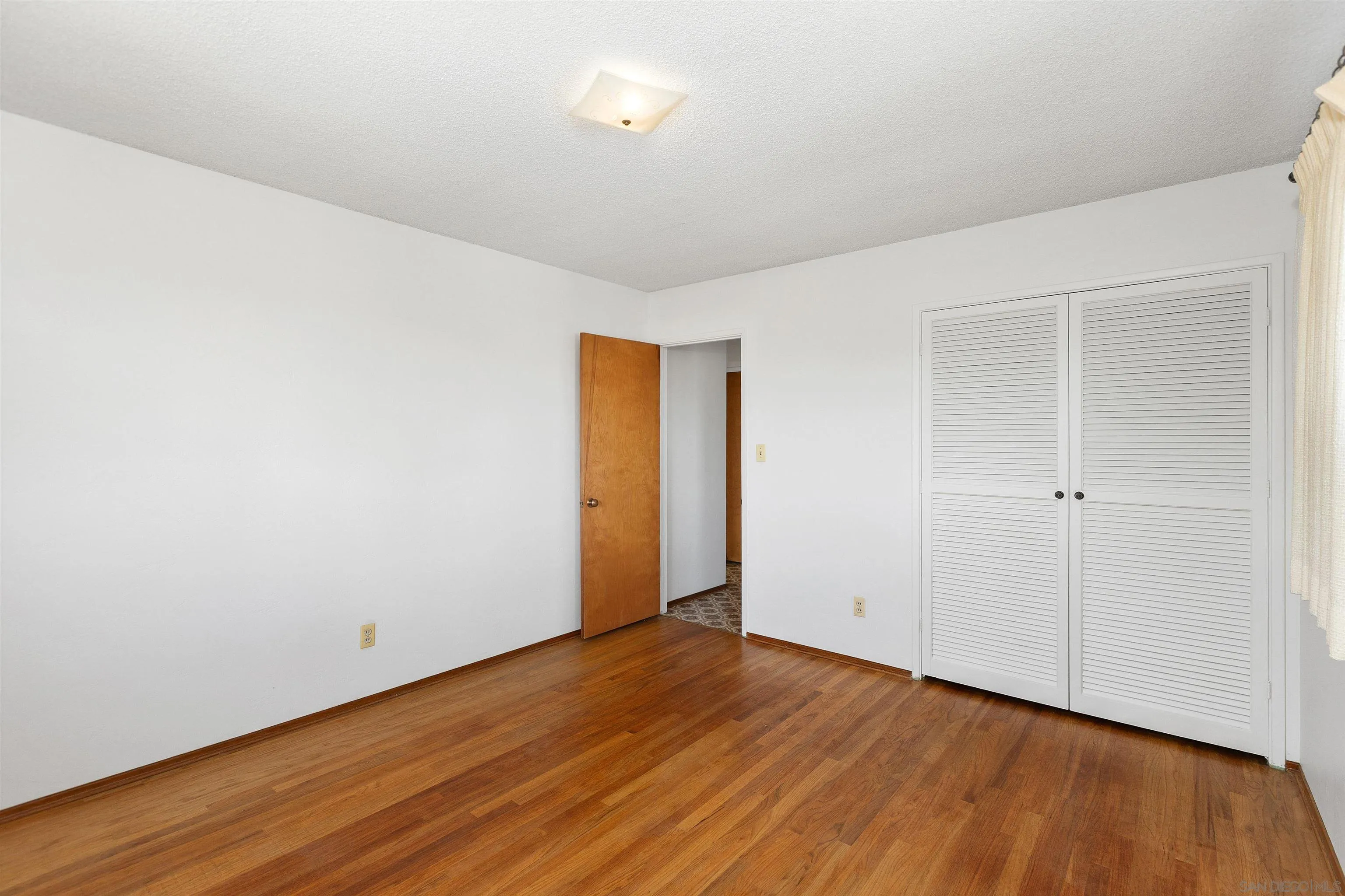 4552 Lucille Drive San Diego, CA 92115 - Photo 14 of 35 a view of an empty room with wooden floor and closet