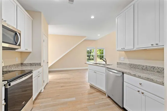 a kitchen with stainless steel appliances granite countertop a sink and dishwasher a stove top oven with wooden floor