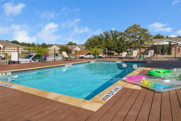 a view of a swimming pool with lawn chairs and plants