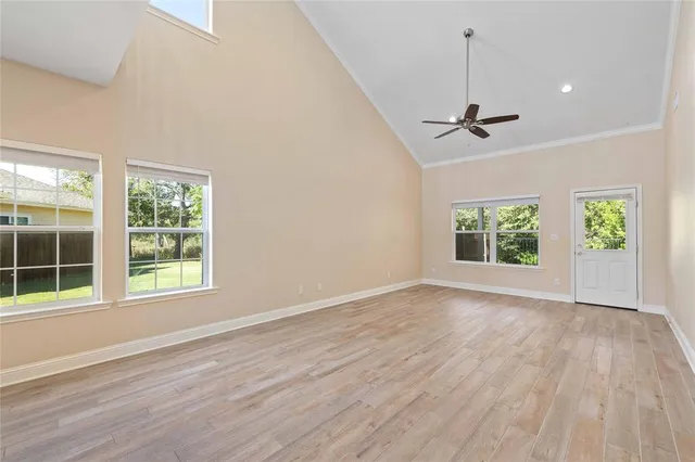 an empty room with wooden floor chandelier and windows