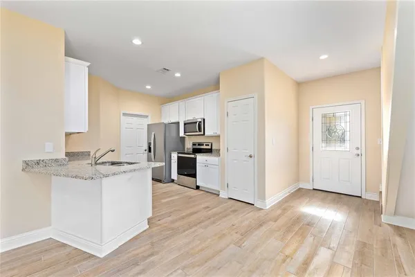 a kitchen with stainless steel appliances kitchen island wooden floors and white cabinets