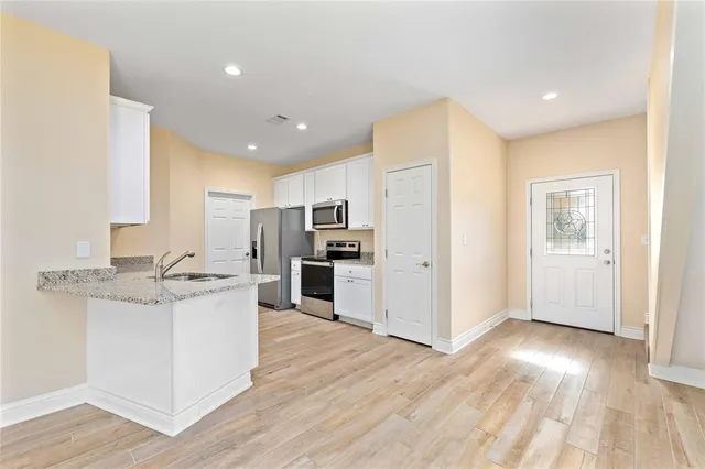 a kitchen with stainless steel appliances kitchen island wooden floors and white cabinets