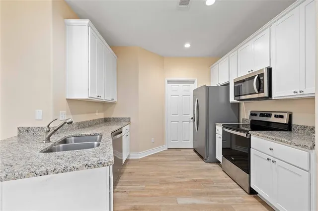 a kitchen with stainless steel appliances granite countertop a sink stove microwave and refrigerator