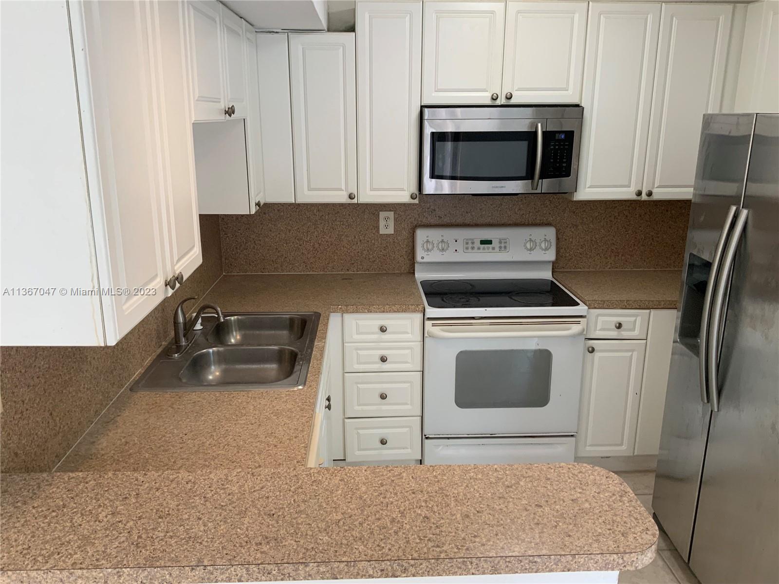8110 Severn Drive, Unit C Boca Raton, FL 33433 - Photo 4 of 31 a kitchen with stainless steel appliances white cabinets and a stove top oven