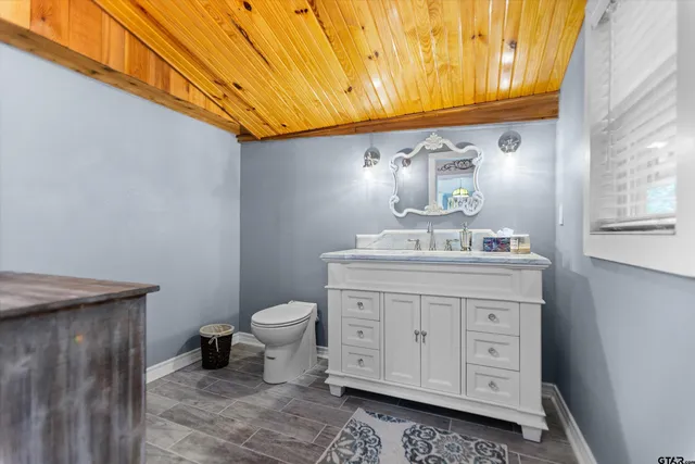 a bathroom with a granite countertop toilet sink and mirror