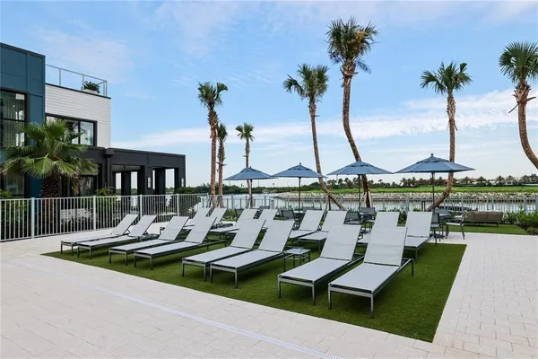 a view of a patio with dining table and chairs with plants and palm trees