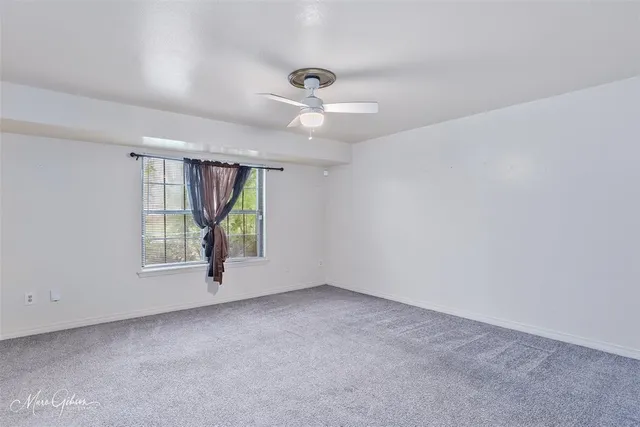 an empty room with windows and ceiling fan