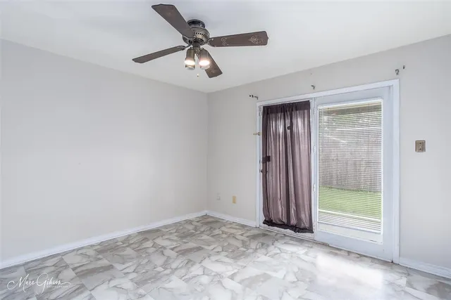 an empty room with a ceiling fan and window