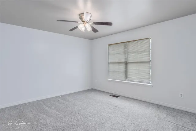 an empty room with windows and chandelier fan