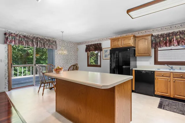 a kitchen with stainless steel appliances granite countertop a refrigerator a stove and a dining table with wooden floor