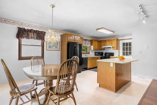 a kitchen with stainless steel appliances kitchen island granite countertop a table chairs and a refrigerator