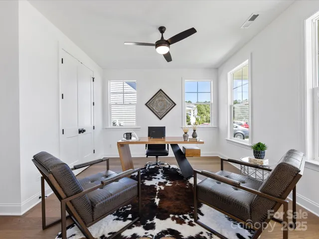a large white open kitchen with stainless steel appliances kitchen island granite countertop a lot of cabinets and wooden floor