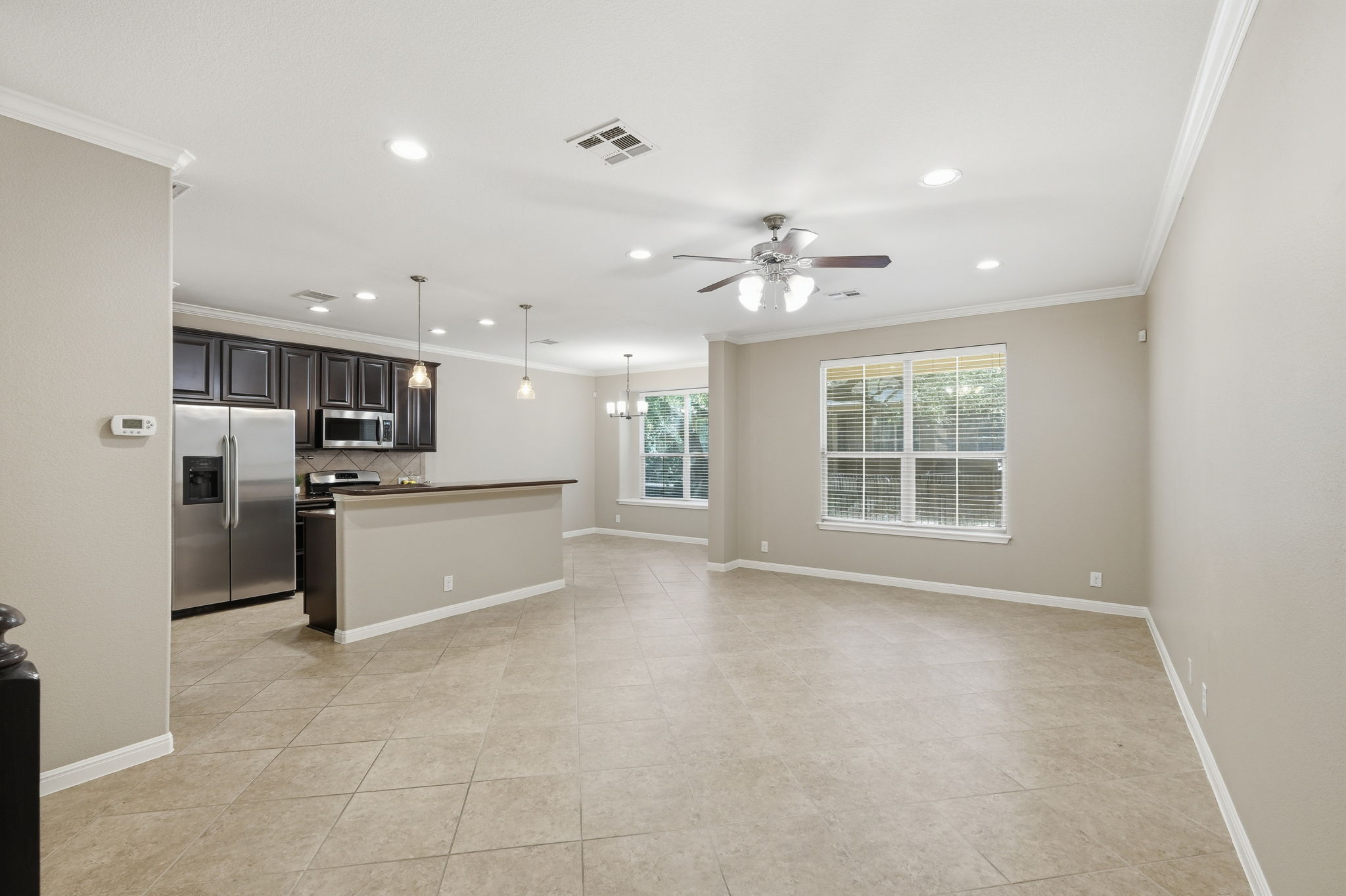 14001 Avery Ranch Boulevard, Unit 602 Austin, TX 78717 - Photo 34 of 39 Kitchen featuring open floor plan, stainless steel appliances, a kitchen island, a ceiling fan, and crown molding