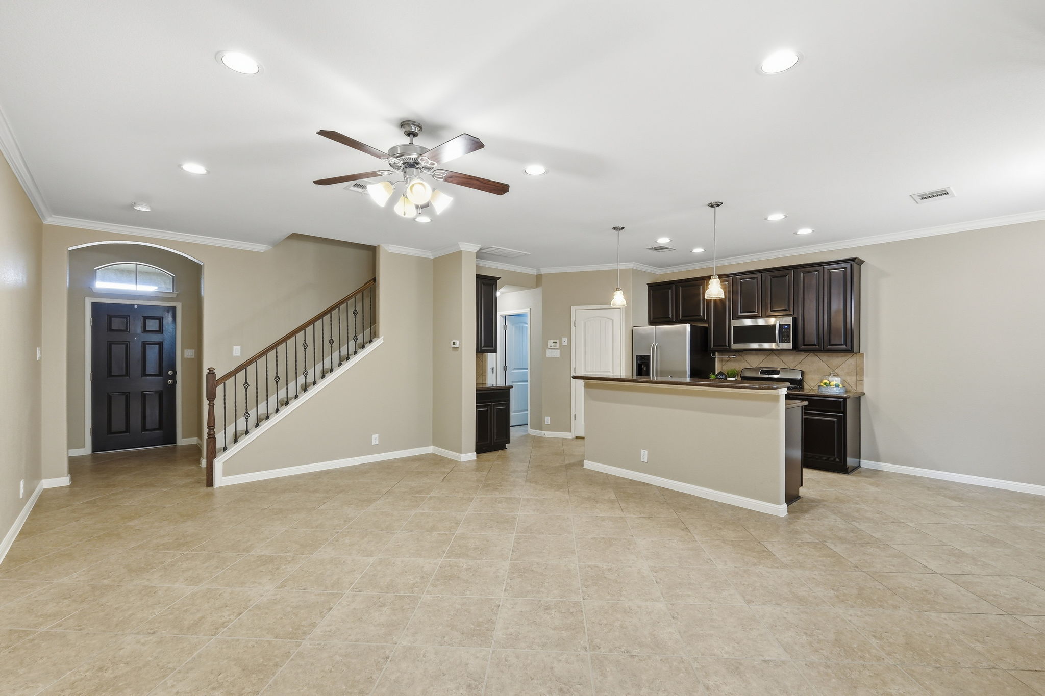 14001 Avery Ranch Boulevard, Unit 602 Austin, TX 78717 - Photo 35 of 39 Kitchen featuring open floor plan, an island with sink, crown molding, ceiling fan, and dark wood finish cabinets