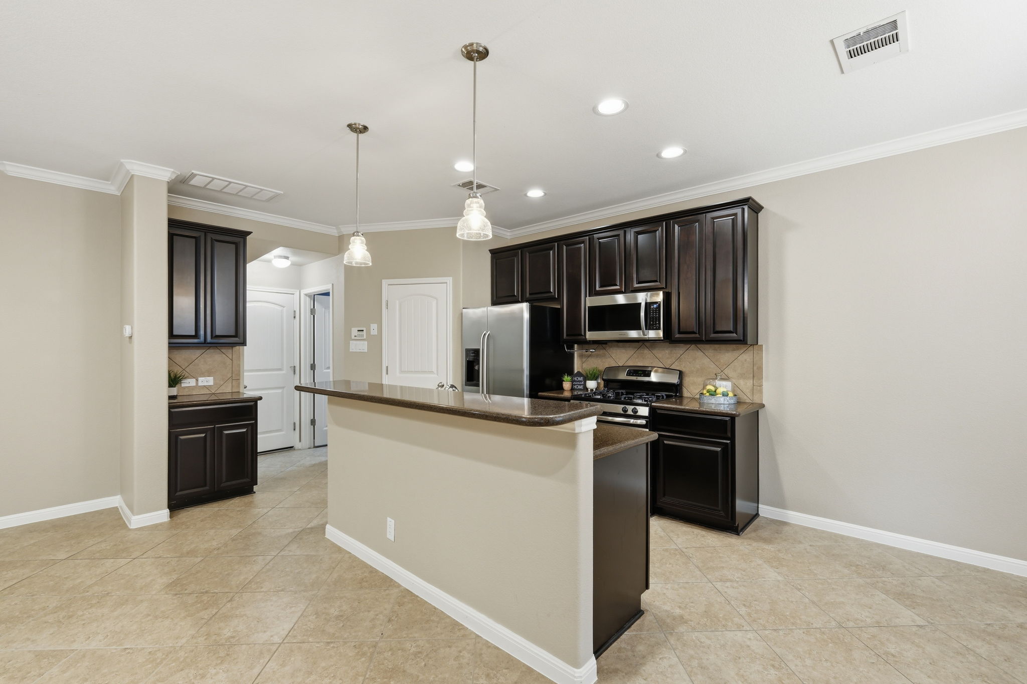 14001 Avery Ranch Boulevard, Unit 602 Austin, TX 78717 - Photo 6 of 39 Kitchen featuring tasteful backsplash, stainless steel appliances, a center island with sink, dark wood finish cabinetry, and light tile patterned flooring