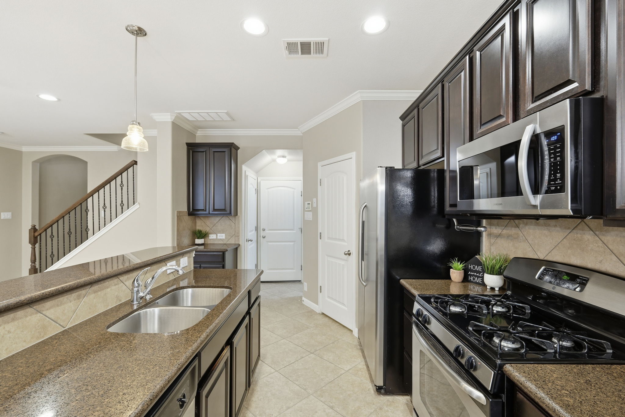 14001 Avery Ranch Boulevard, Unit 602 Austin, TX 78717 - Photo 7 of 39 Kitchen with stainless steel appliances, crown molding, pendant lighting, dark stone counters, and tasteful backsplash