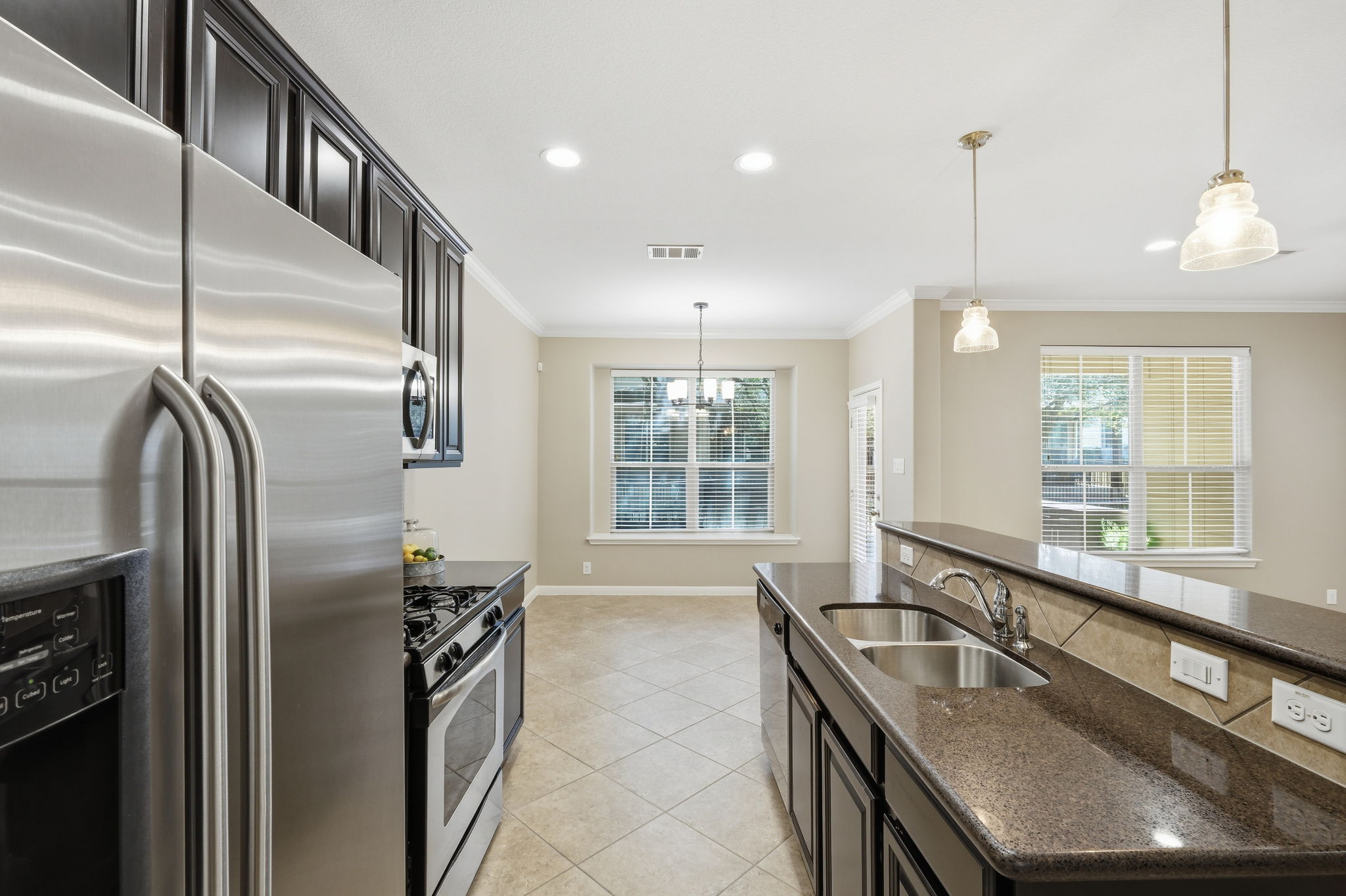 14001 Avery Ranch Boulevard, Unit 602 Austin, TX 78717 - Photo 8 of 39 Kitchen with stainless steel appliances, dark stone countertops, a center island with sink, light tile patterned floors, and ornamental molding