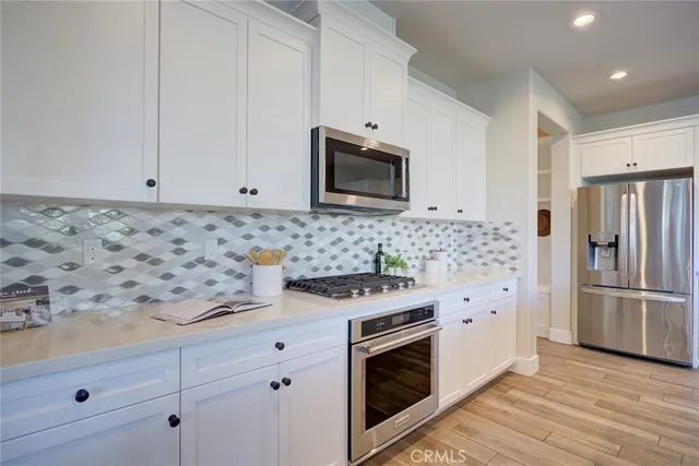 a kitchen with granite countertop white cabinets stainless steel appliances and wooden floor