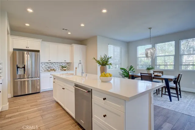 a kitchen with stainless steel appliances kitchen island granite countertop a table chairs and a refrigerator