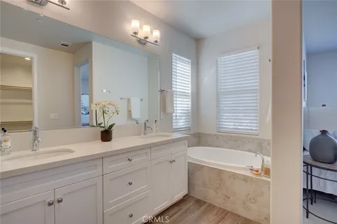 a bathroom with double vanity a window a mirror and a bathtub