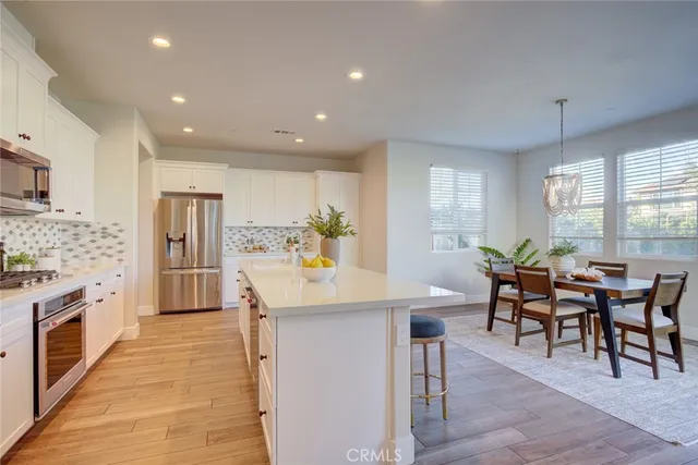 a kitchen with stainless steel appliances kitchen island granite countertop a stove a sink a dining table and chairs