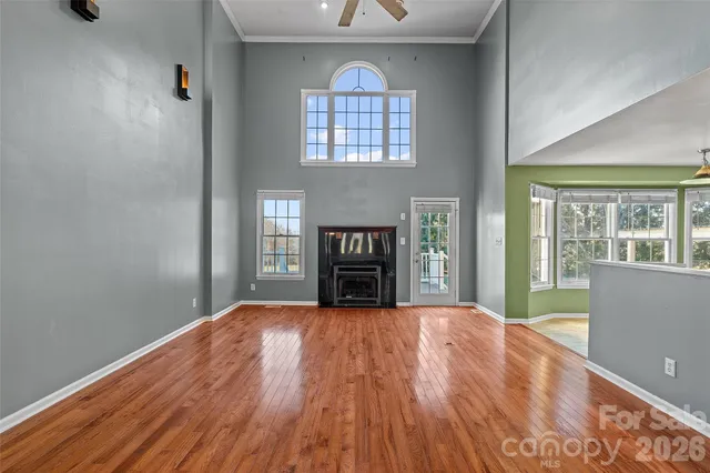 a view of an empty room with wooden floor fireplace and a window