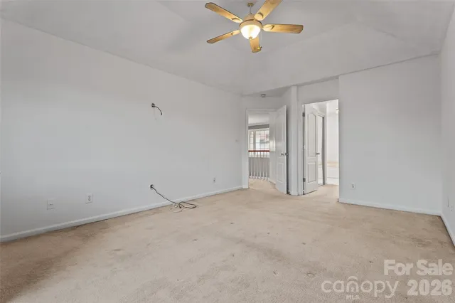 an empty room with chandelier fan and windows