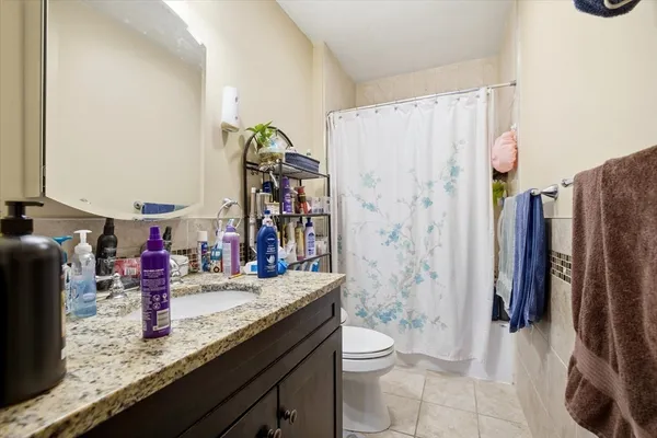 a bathroom with a granite countertop sink a toilet and shower