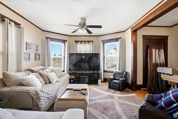 a living room with furniture a ceiling fan and a flat screen tv
