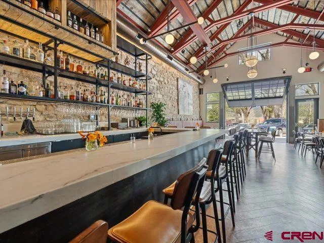 a dining hall with stainless steel appliances granite countertop a table chairs and a wooden floor