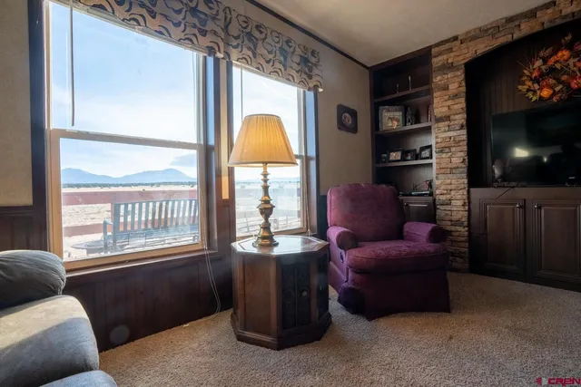 a living room with furniture a flat screen tv and a floor to ceiling window