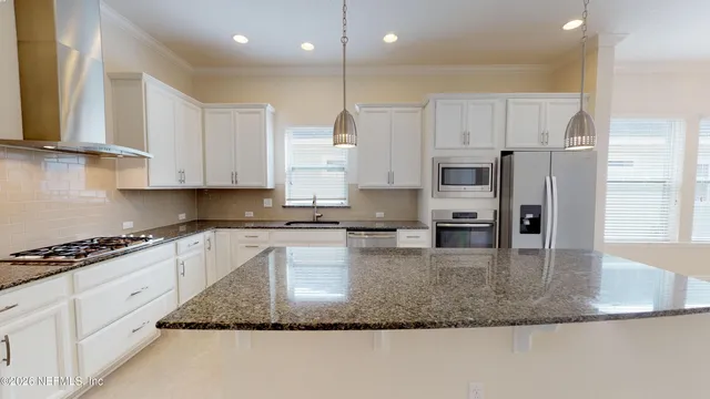 a kitchen with stainless steel appliances granite countertop a sink refrigerator and cabinets