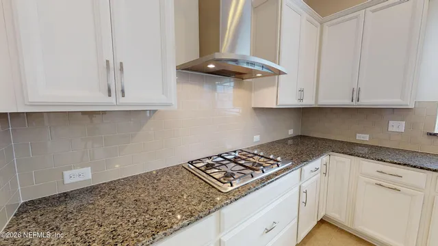 a kitchen with granite countertop white cabinets and a stove