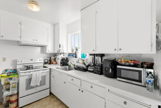 a kitchen with white cabinets and white appliances