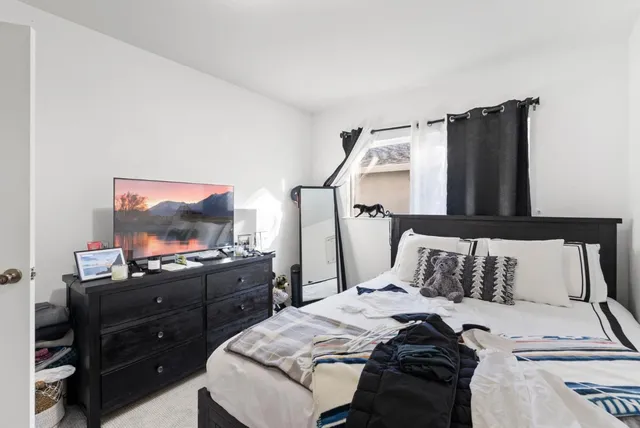 a bedroom with a bed and a flat tv screen on a dresser