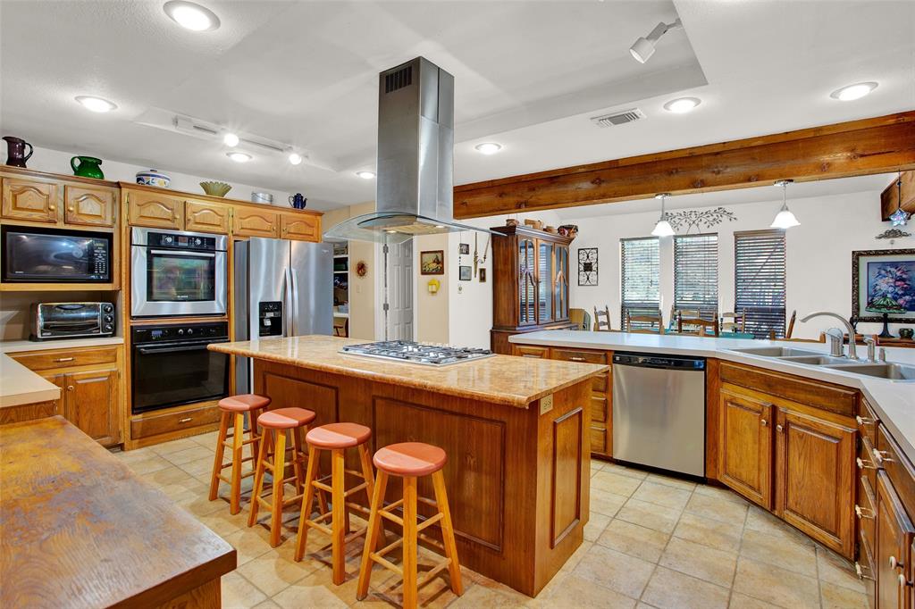 7146 Refuge Road Pottsboro, TX 75076 - Photo 18 of 39 a large kitchen with stainless steel appliances kitchen island granite countertop a sink and cabinets