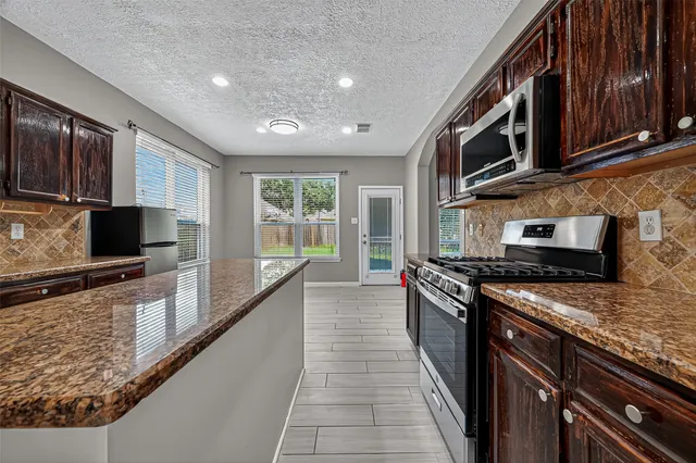 a large kitchen with stainless steel appliances granite countertop a stove a sink and a microwave