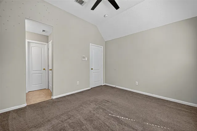 an empty room with closet and a ceiling fan