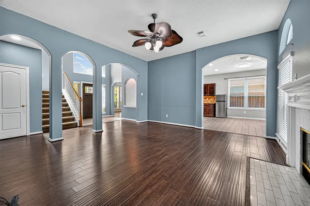 an empty room with wooden floor chandelier and windows