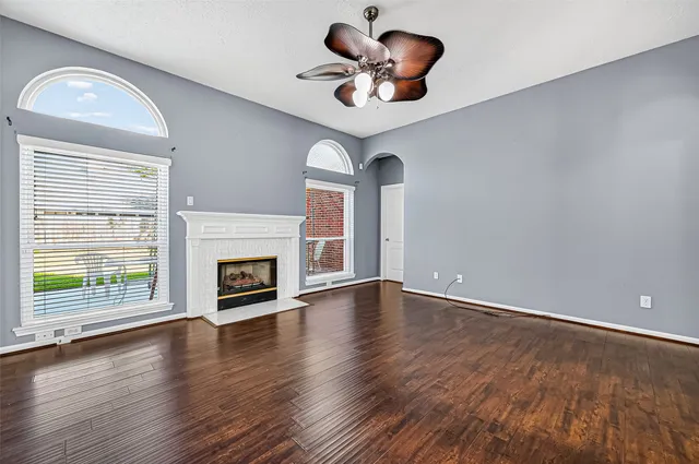 an empty room with wooden floor fireplace and windows