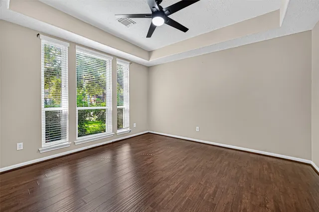 a view of an empty room with wooden floor and a window