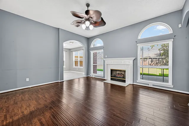an empty room with wooden floor fireplace and windows