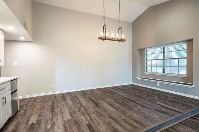 a view of kitchen and empty room with wooden floor