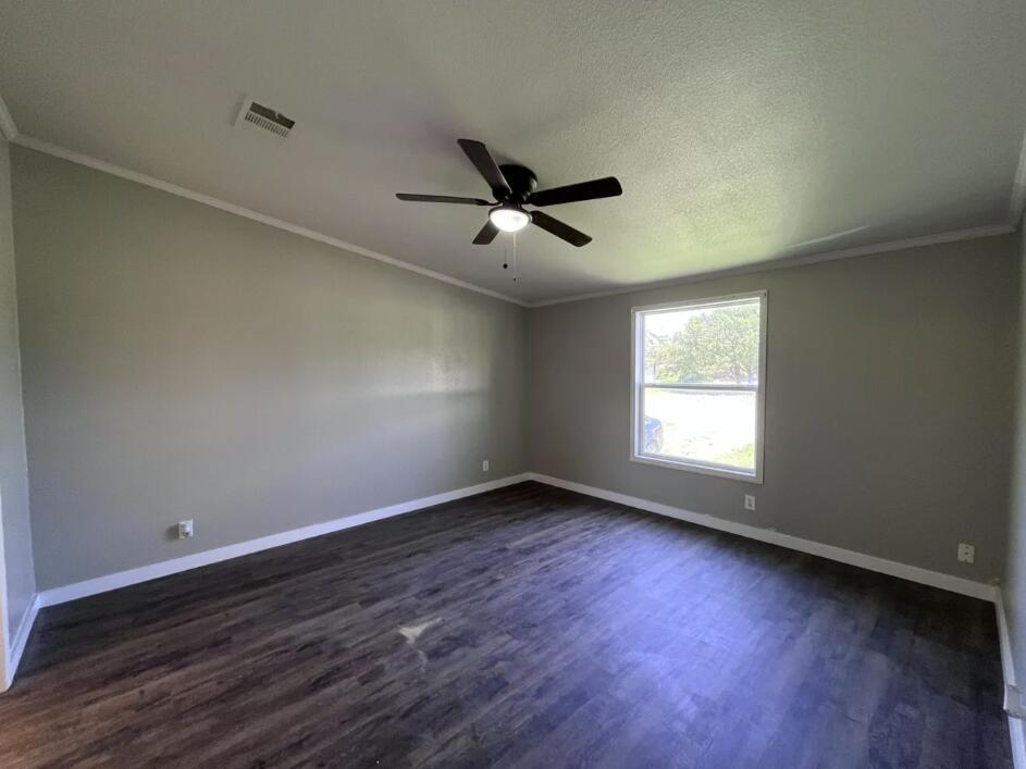 107 Grant Street Smyer, TX 79367 - Photo 13 of 22 an empty room with wooden floor and windows