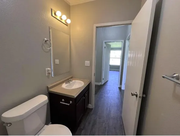 a bathroom with a granite countertop sink toilet a mirror and vanity