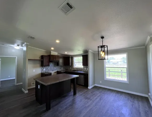 a kitchen with kitchen island granite countertop a sink cabinets and wooden floor