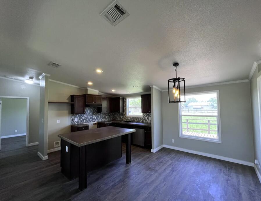 107 Grant Street Smyer, TX 79367 - Photo 9 of 22 a kitchen with kitchen island granite countertop a sink cabinets and wooden floor