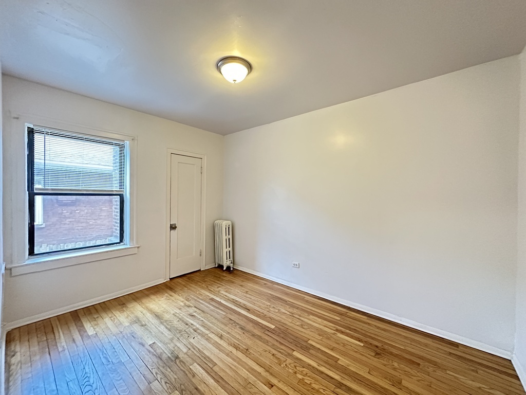 7149 South Constance Avenue, Unit 1E Chicago, IL 60649 - Photo 16 of 20 an empty room with wooden floor and windows